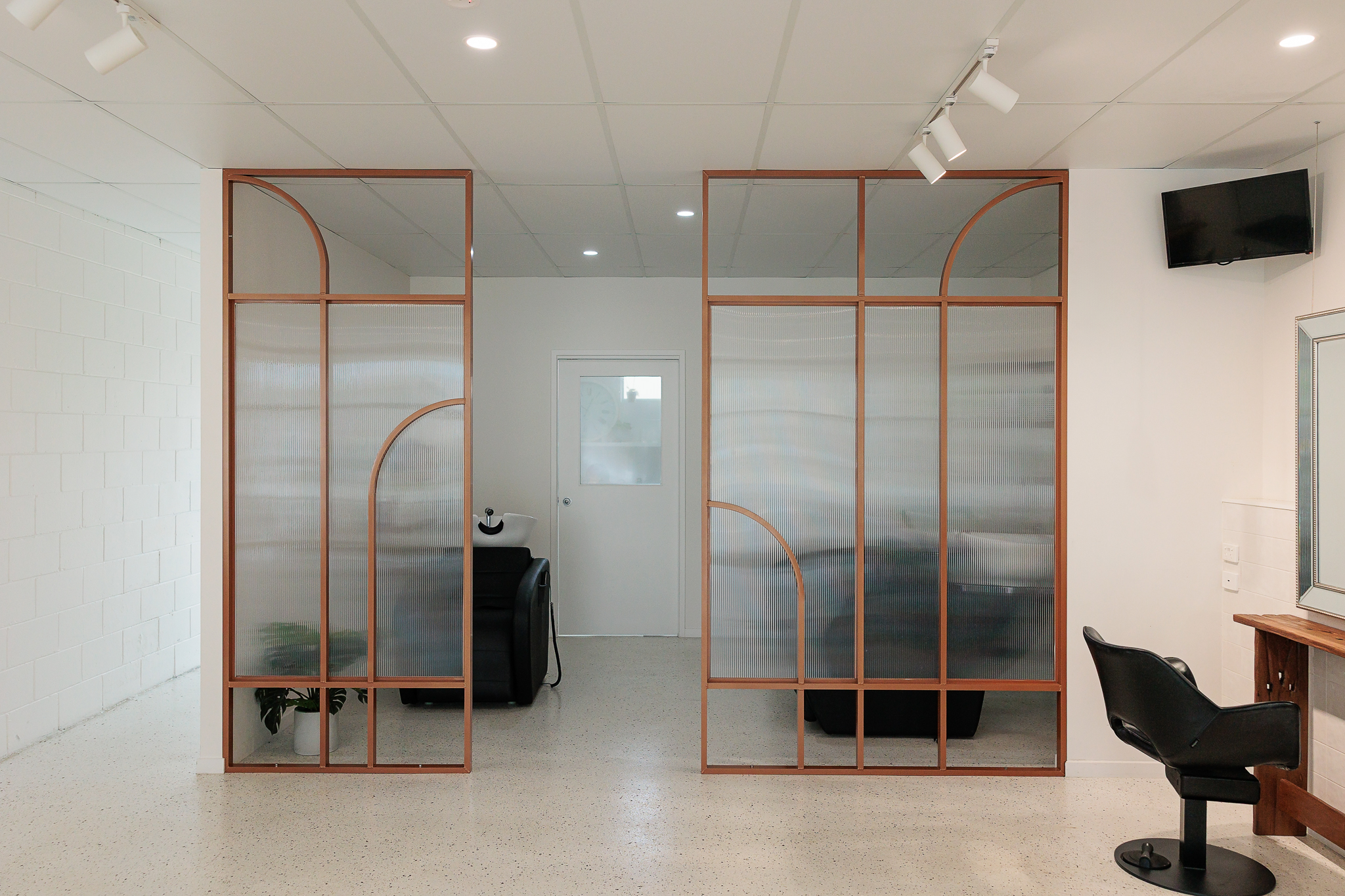 About Hair Mackay salon interior featuring arched glass partitions and styling stations